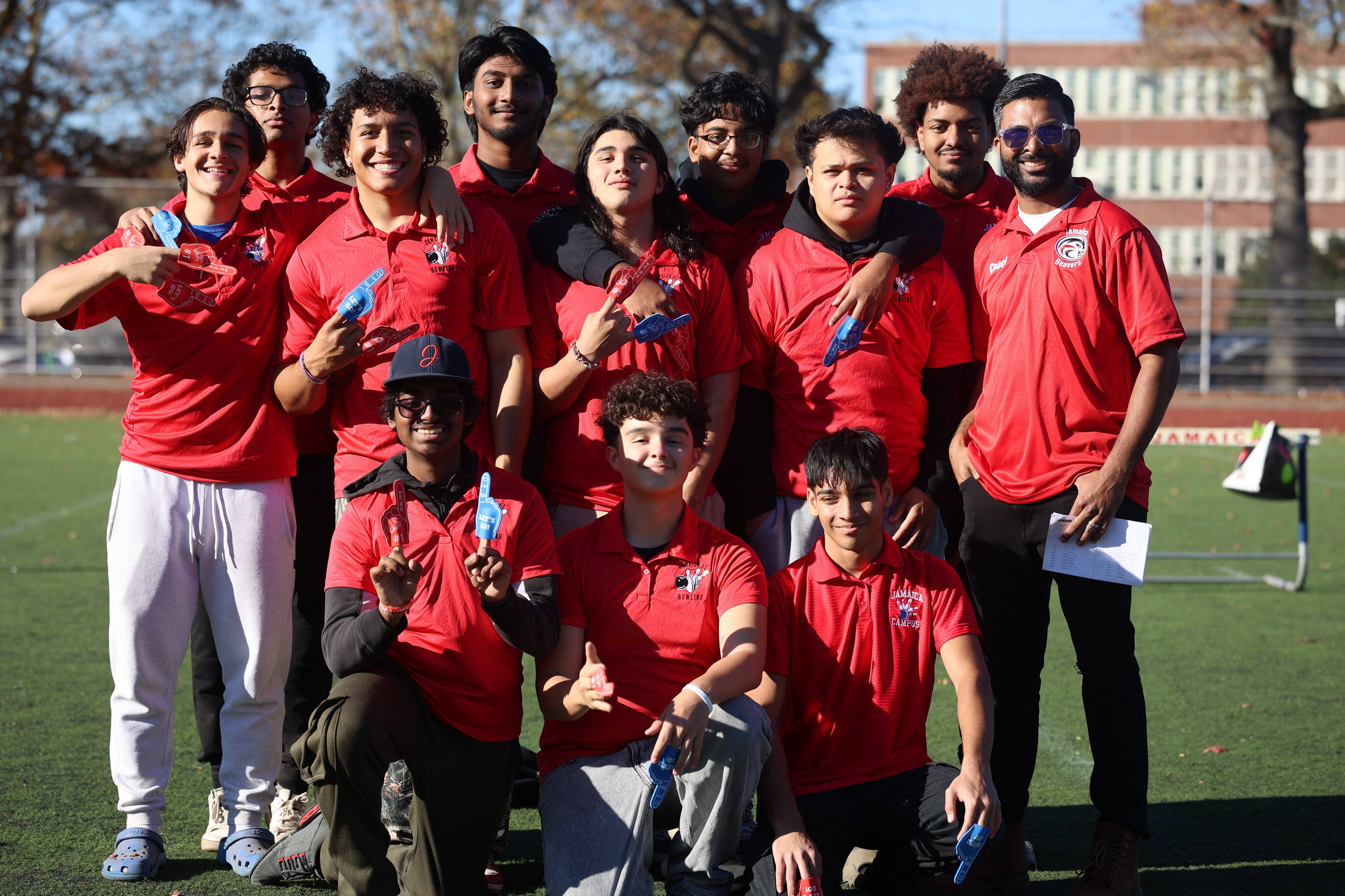 Students and coach in red uniforms posing on athletic field