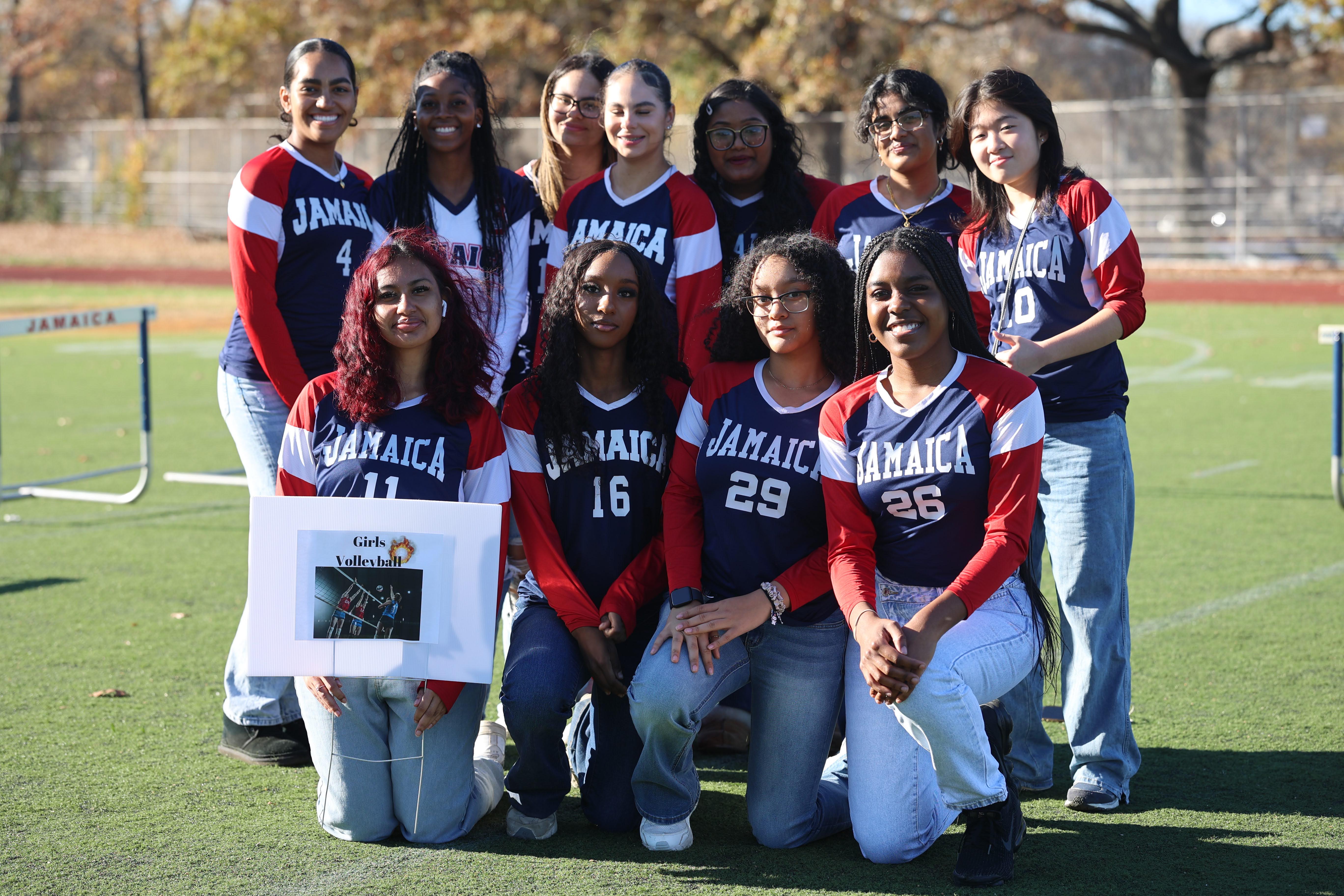 Jamaica High School girls volleyball team posing outdoors on athletic field