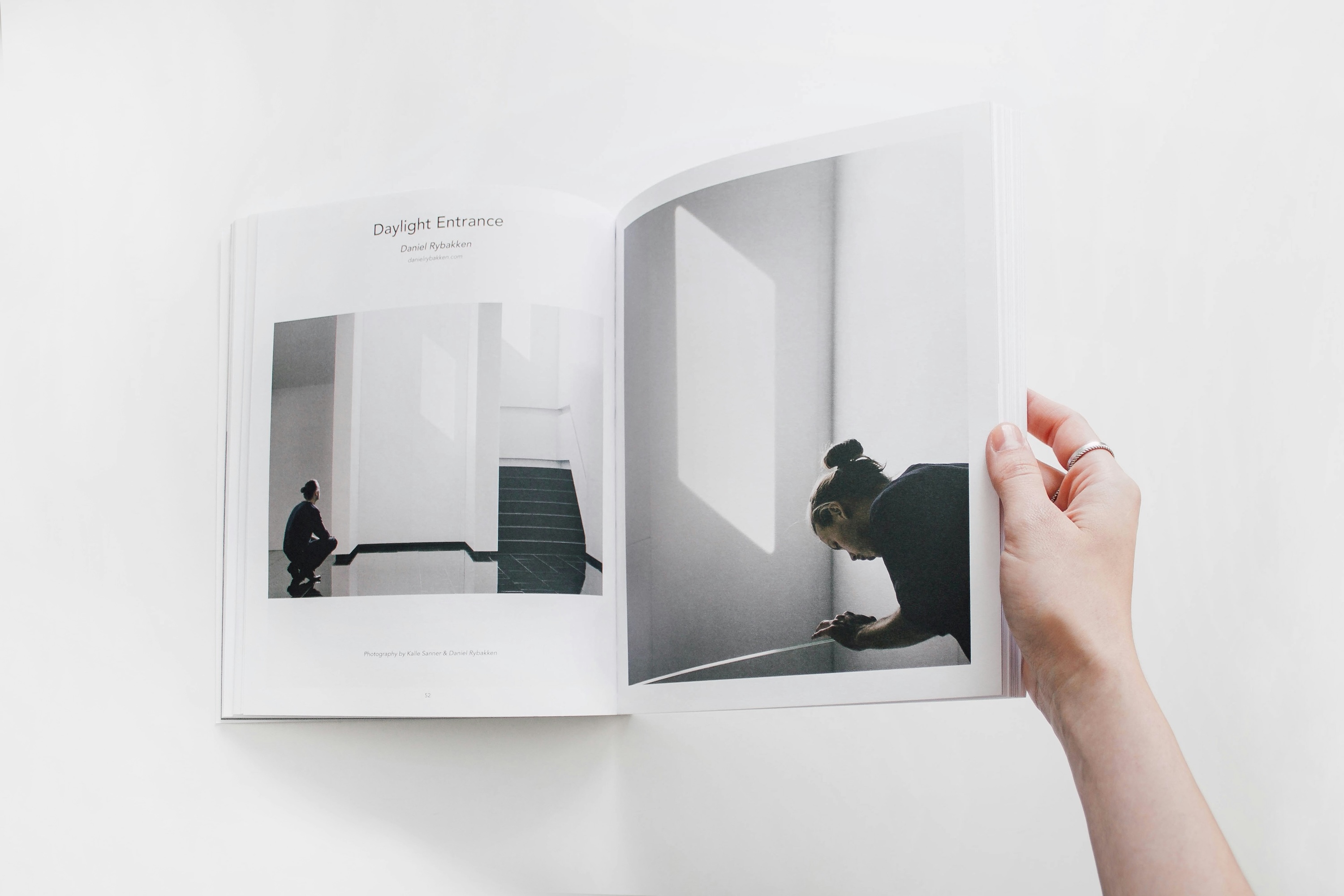 A hand paging through an art book in a minimalist setting.