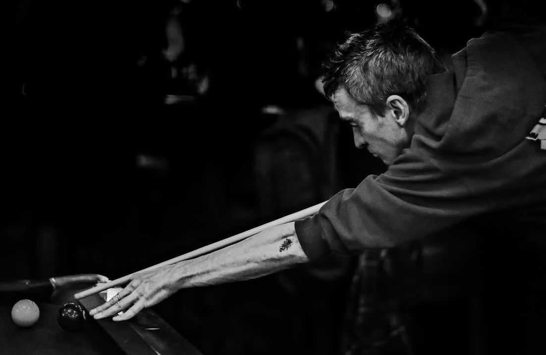 Jacob aligning pool cue, pool ball and line of sight for a perfect shot