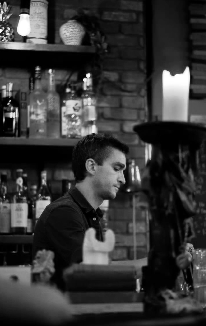 A decorative frog sconce sitting on the bar with a bartender behind it