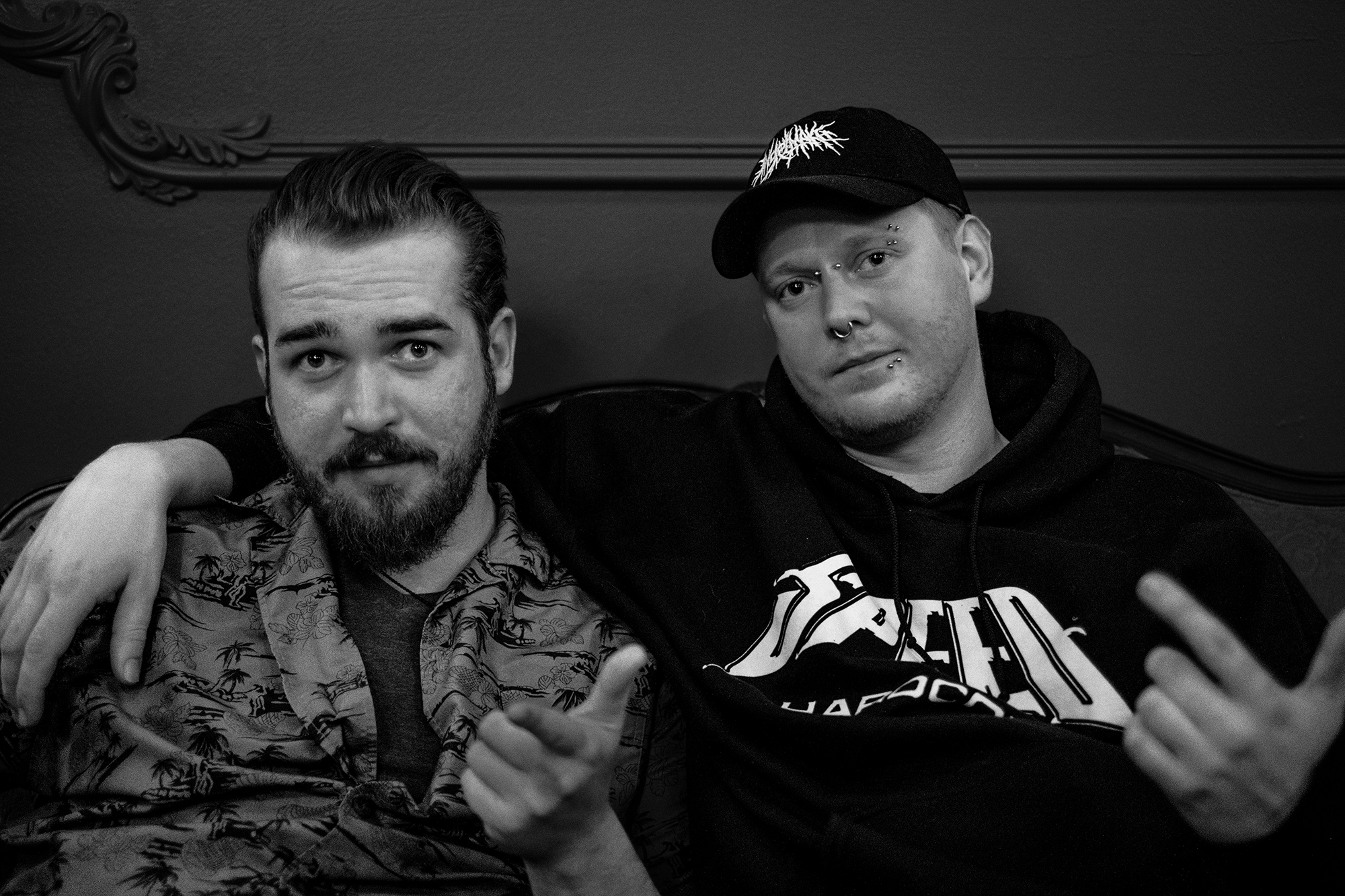 Sean and Austin on a couch pointing with finger guns