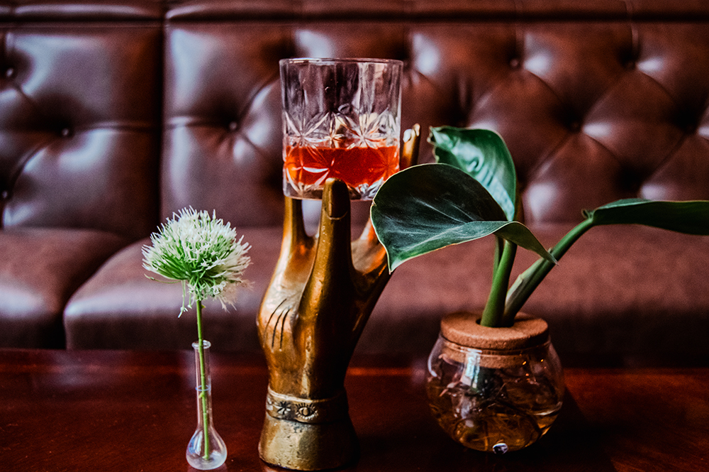 A picture of an old fashioned cocktail and some of the bedlam plants sitting by the banquet