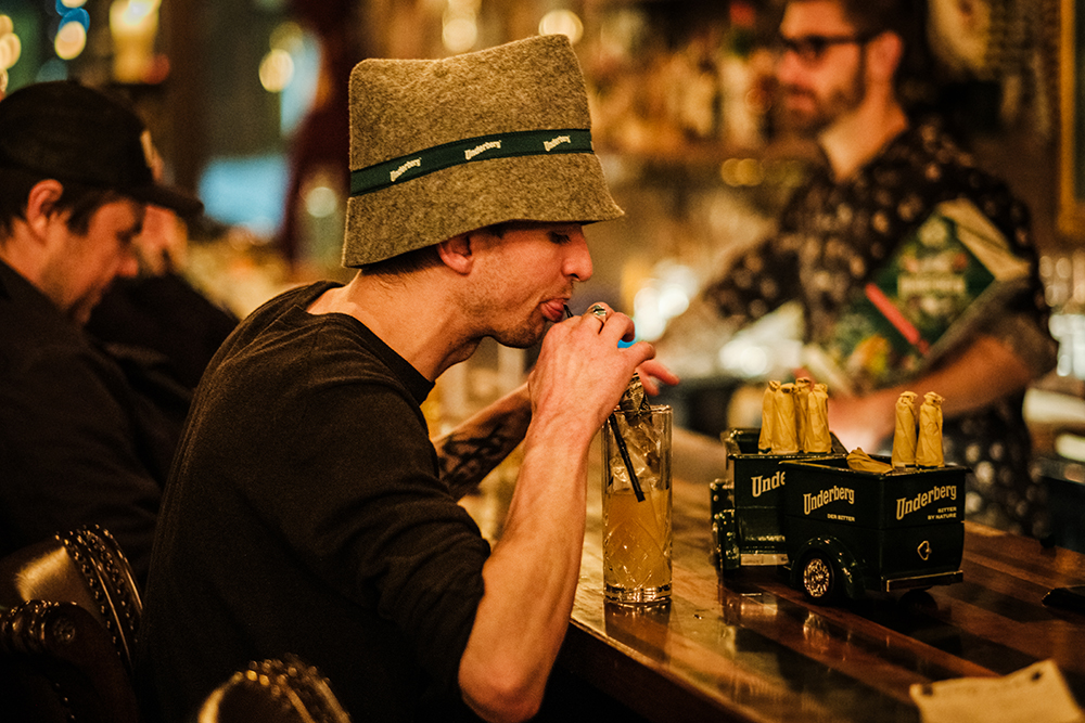 Owner Jacob Berndt wearing a silly hat sipping a drink with a straw