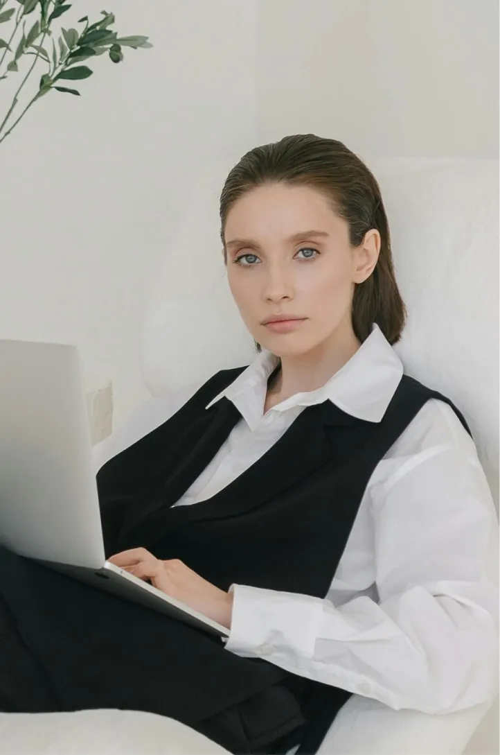 A woman sitting on a sofa with a laptop on her lap