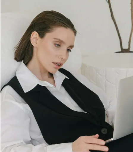 A woman sitting on a sofa looking at her laptop.