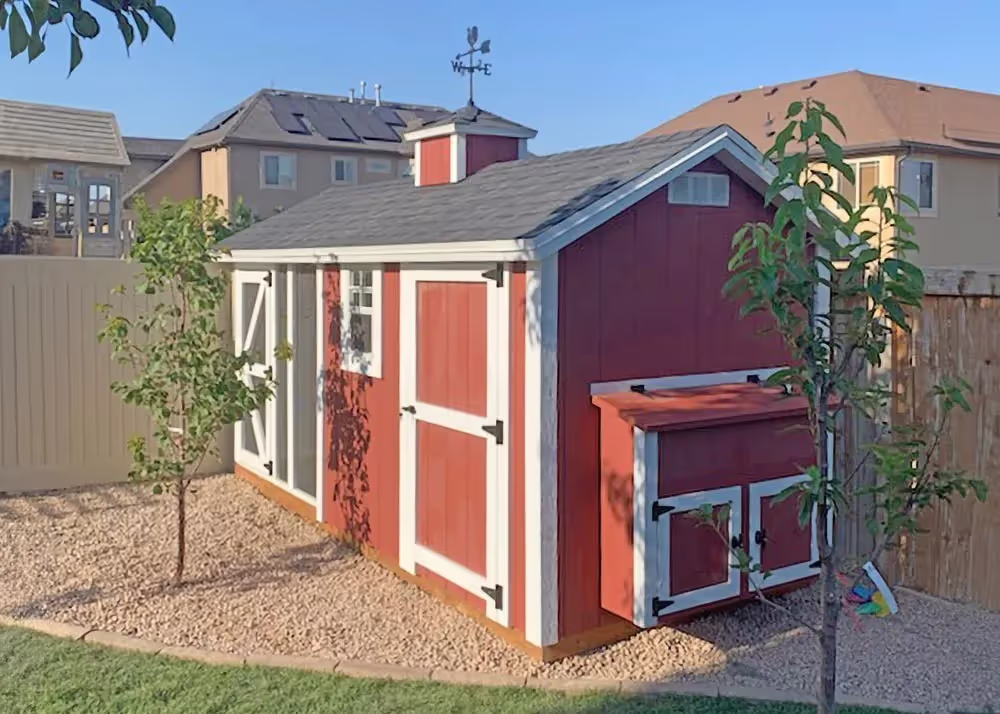 A red and white 6 foot by 14 foot Coop De'Ville chicken coop with cabinet nesting box on end