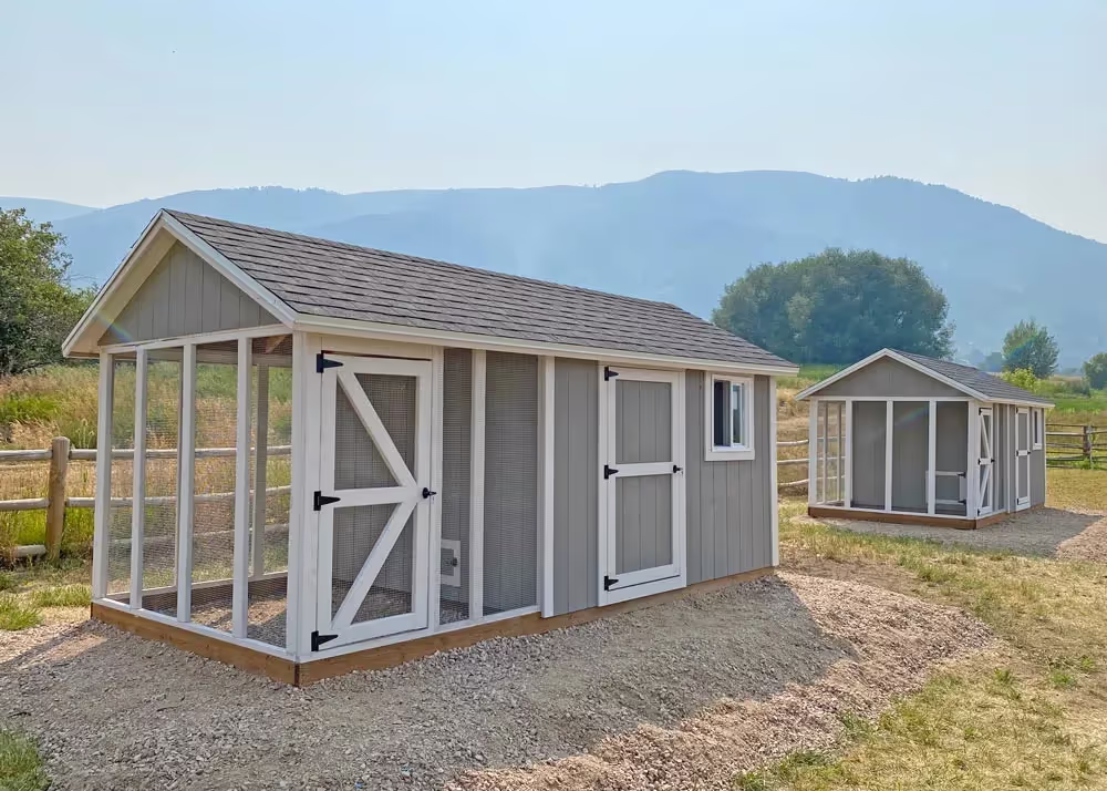 A pair of 8 foot by 16 foot gray and white Coop DeVille chicken coop