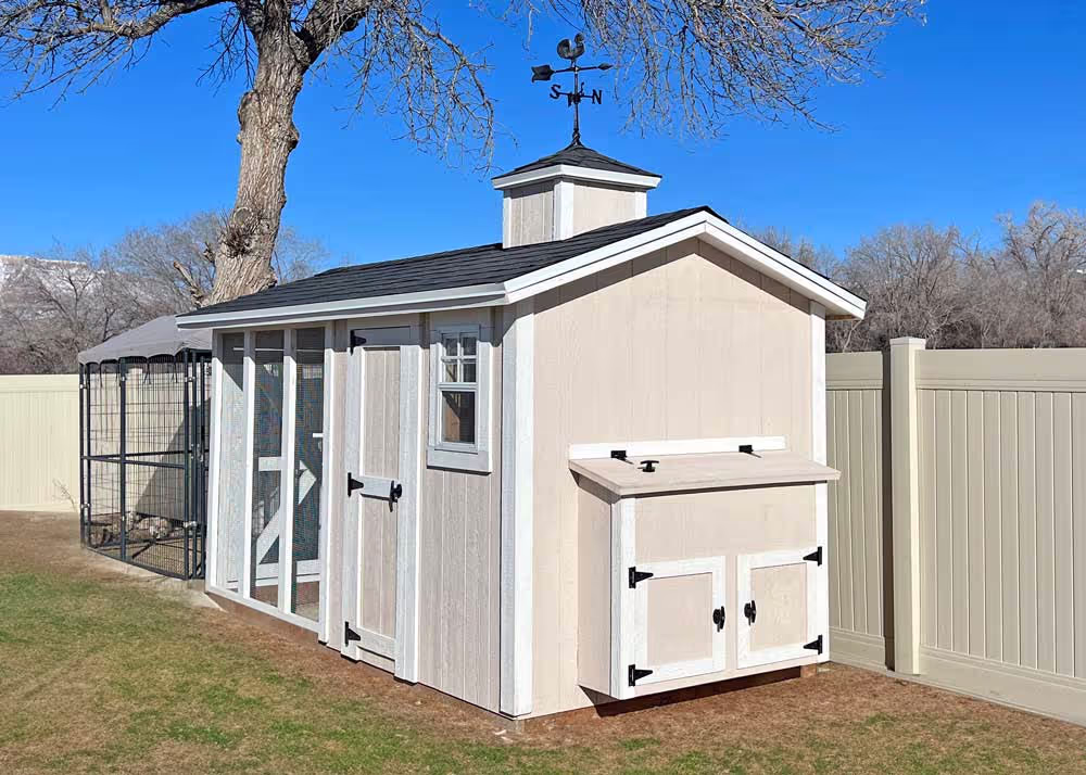 A 6 foot by 12 foot Coop De'Ville chicken Coop in Tan and White with a cupola and weathervane