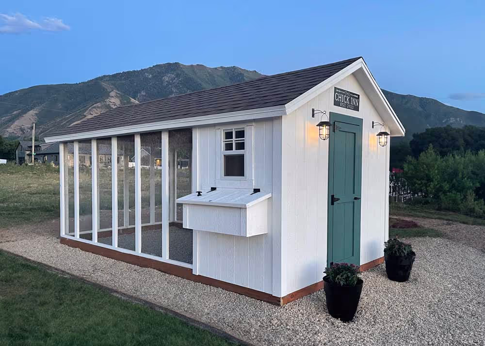 An 8 foot by 16 foot Coop De'Ville in white with a green door and lights
