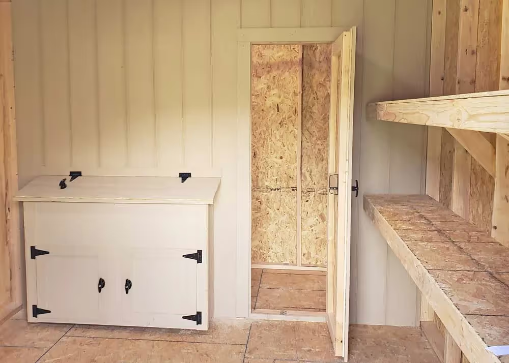 An interior divider wall on a custom shed/chicken coop with a door and a nesting box cabinet