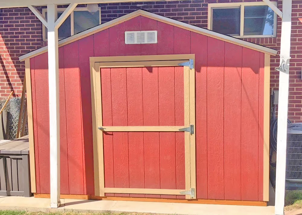 Red and tan 10 by 8 Value Apex shed beneath a covered patio