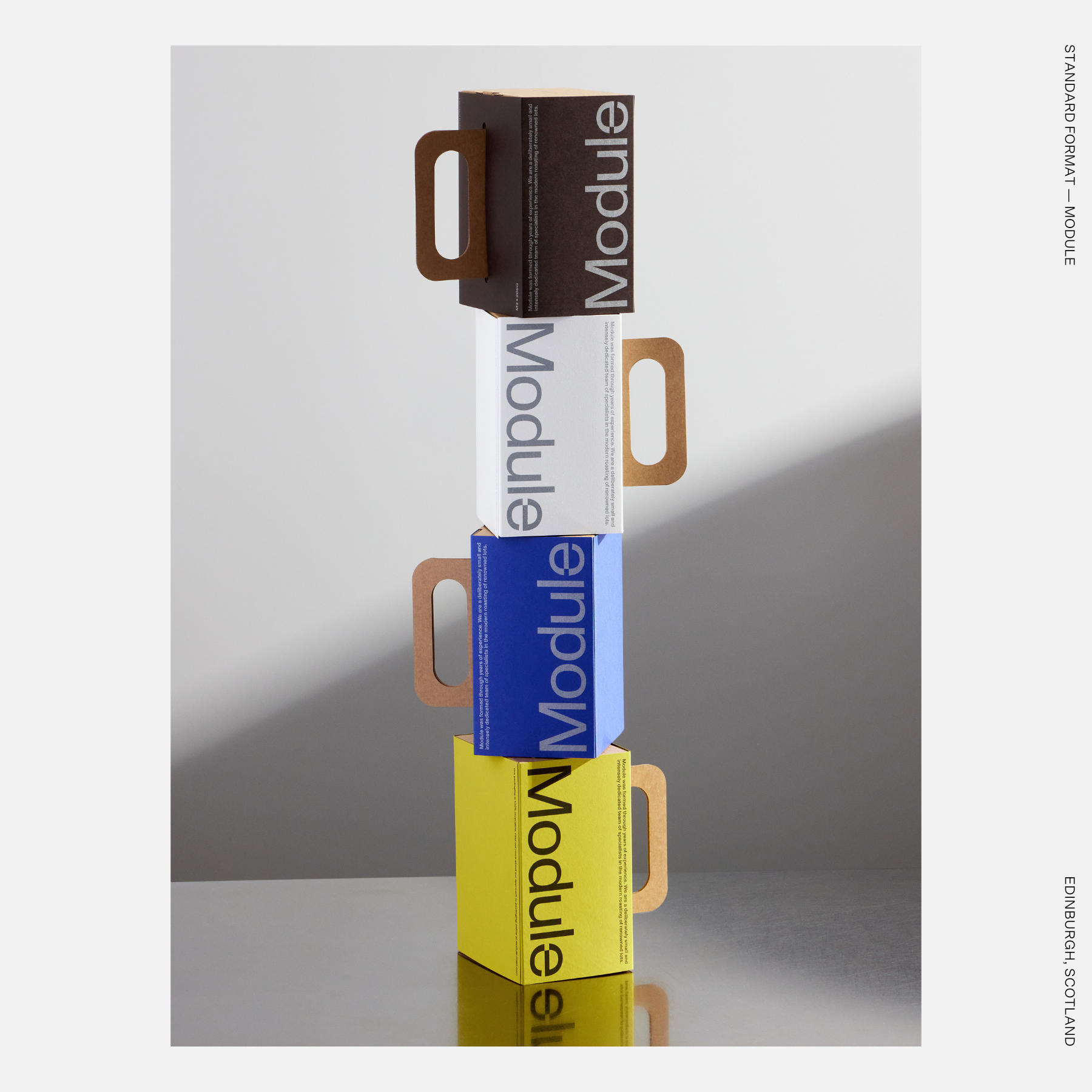 Stacked modular product boxes in brown, white, blue, and yellow with integrated handles and oversized vertical typography.