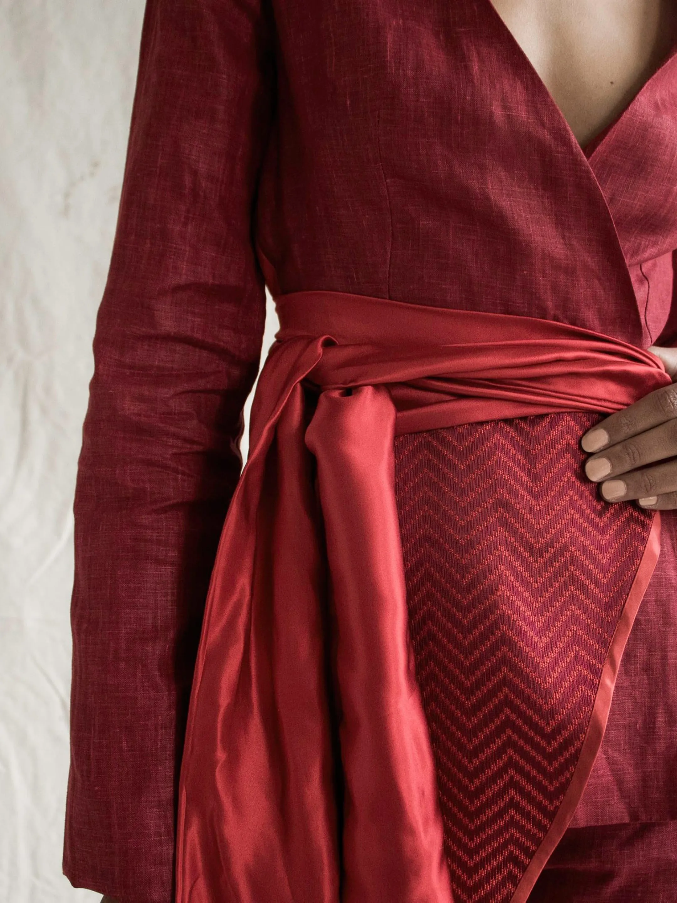 Close-up of a red wrap outfit with a shiny sash and patterned panel.