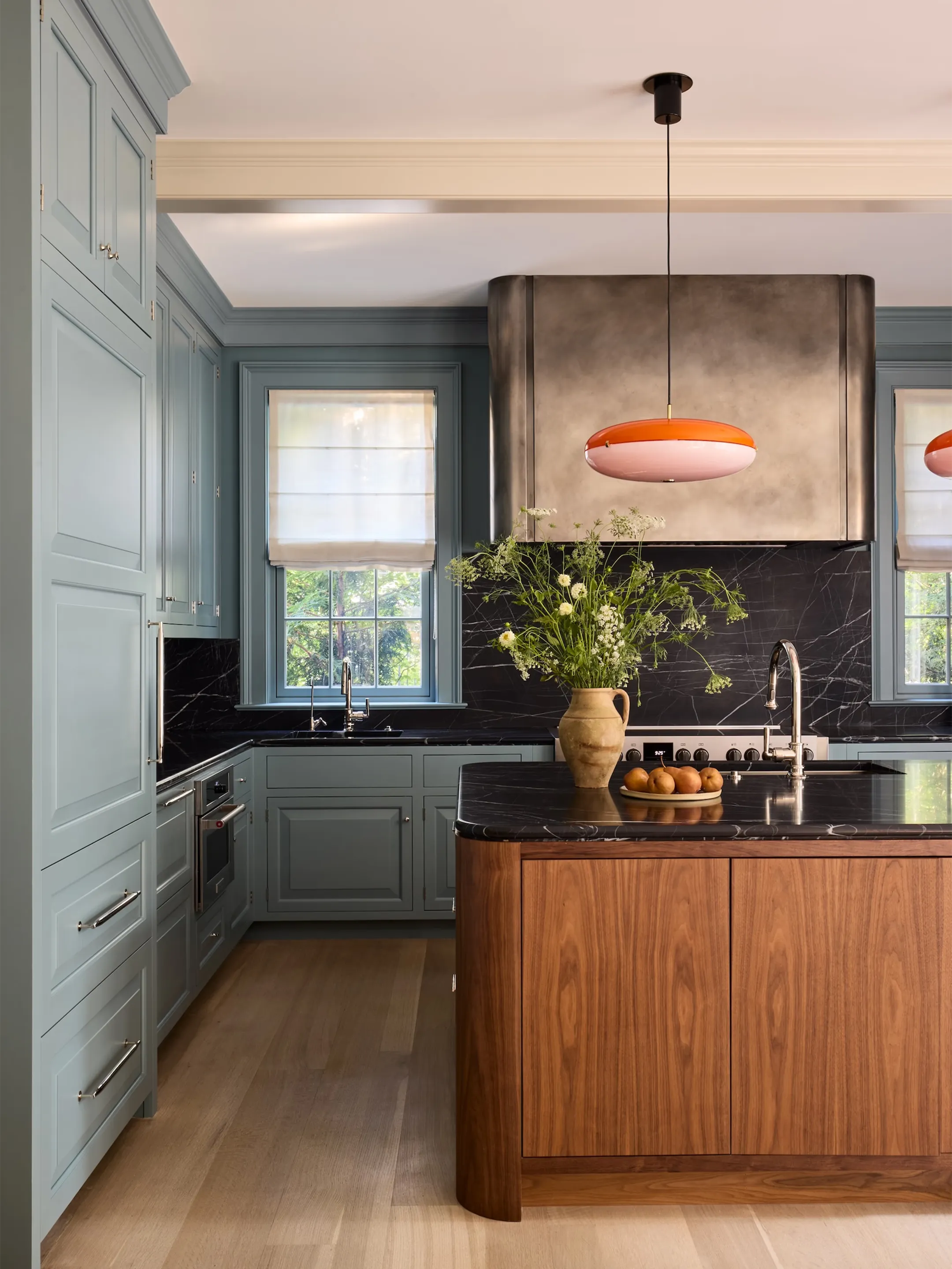 Kitchen with blue cabinetry, a wood island, and orange pendant lights.