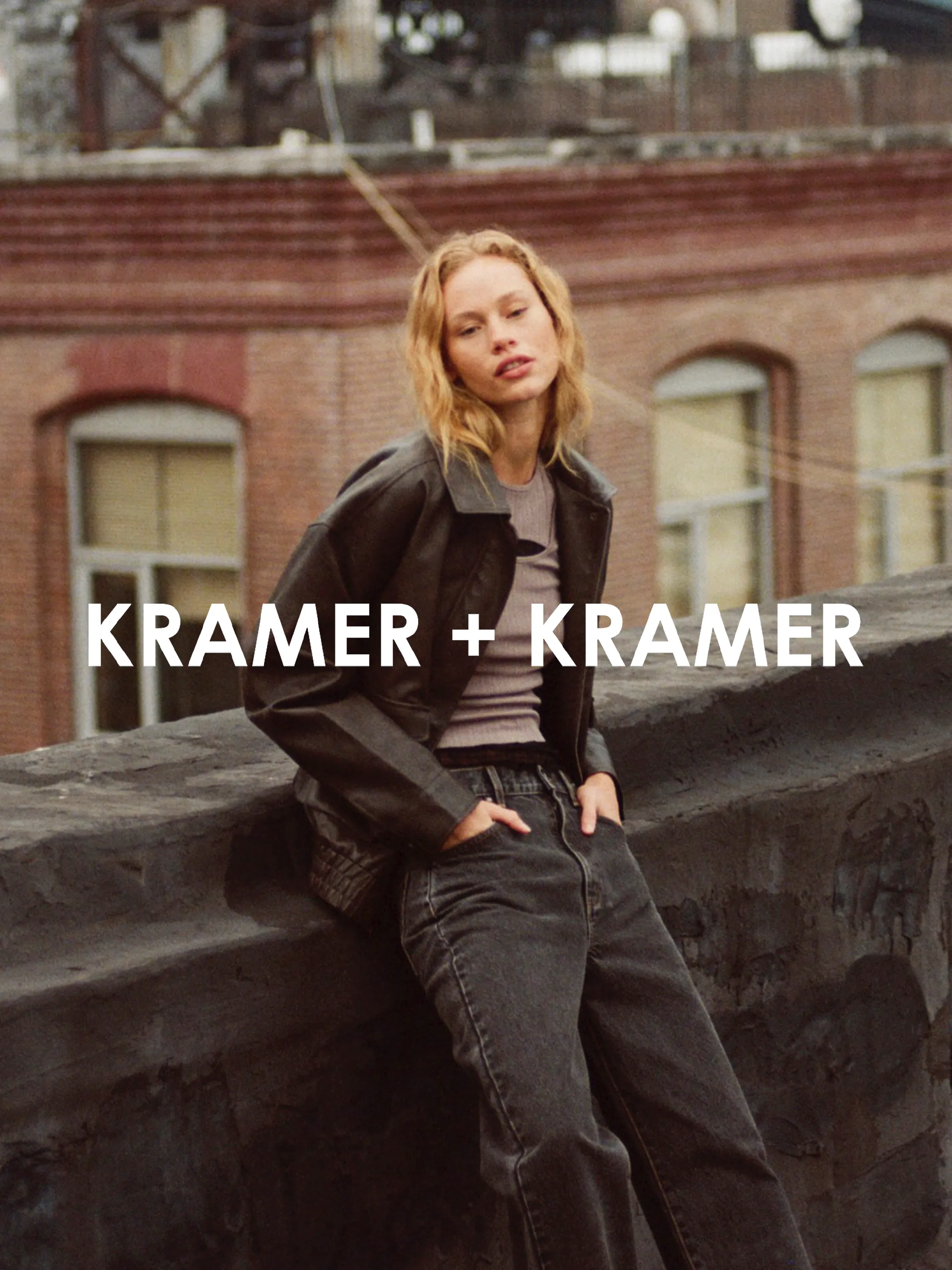 Kramer + Kramer wordmark over a model in a dark jacket leaning against a rooftop wall.
