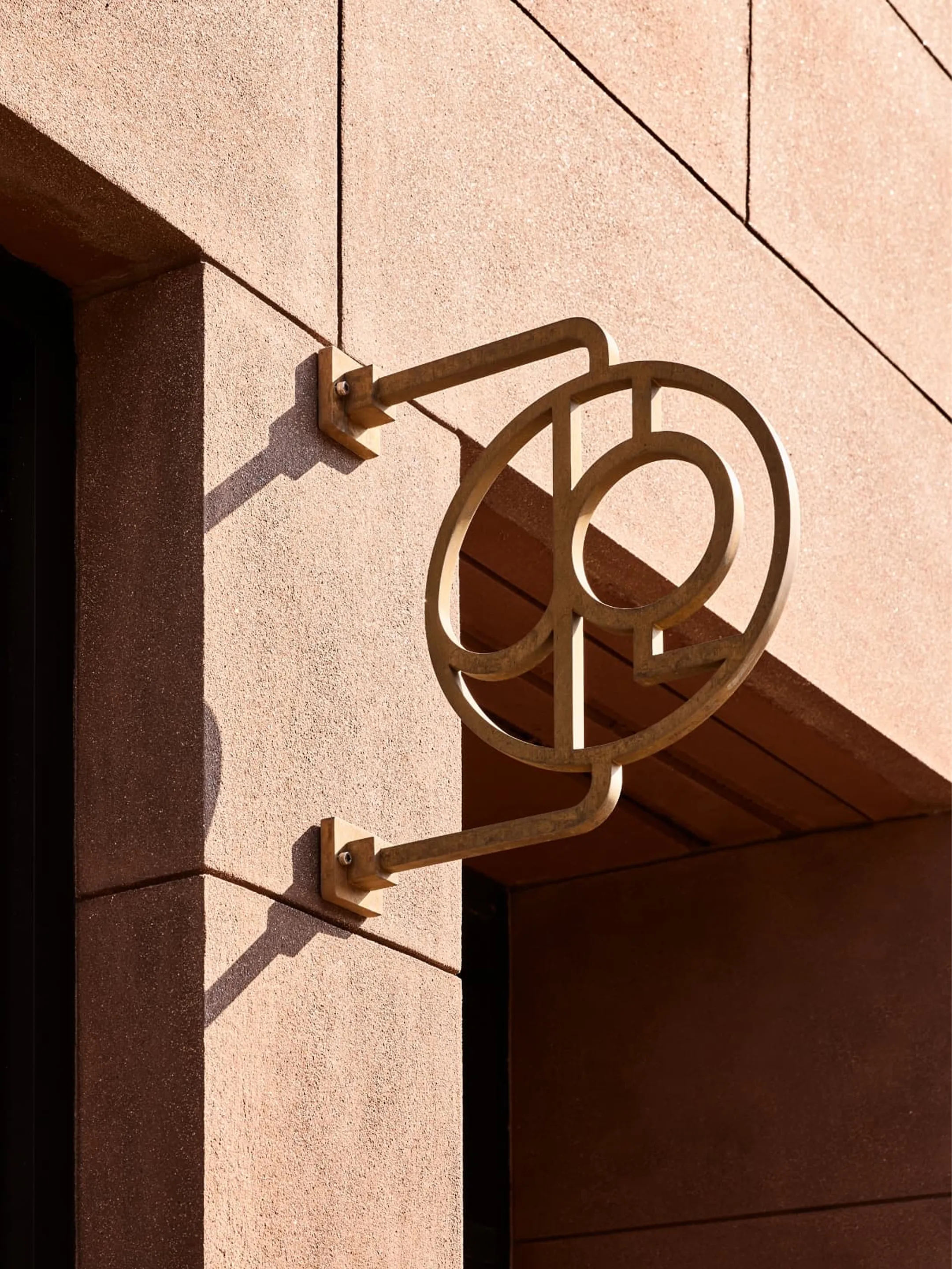 Sculptural Jesse Parris-Lamb monogram sign mounted beside a stone doorway.