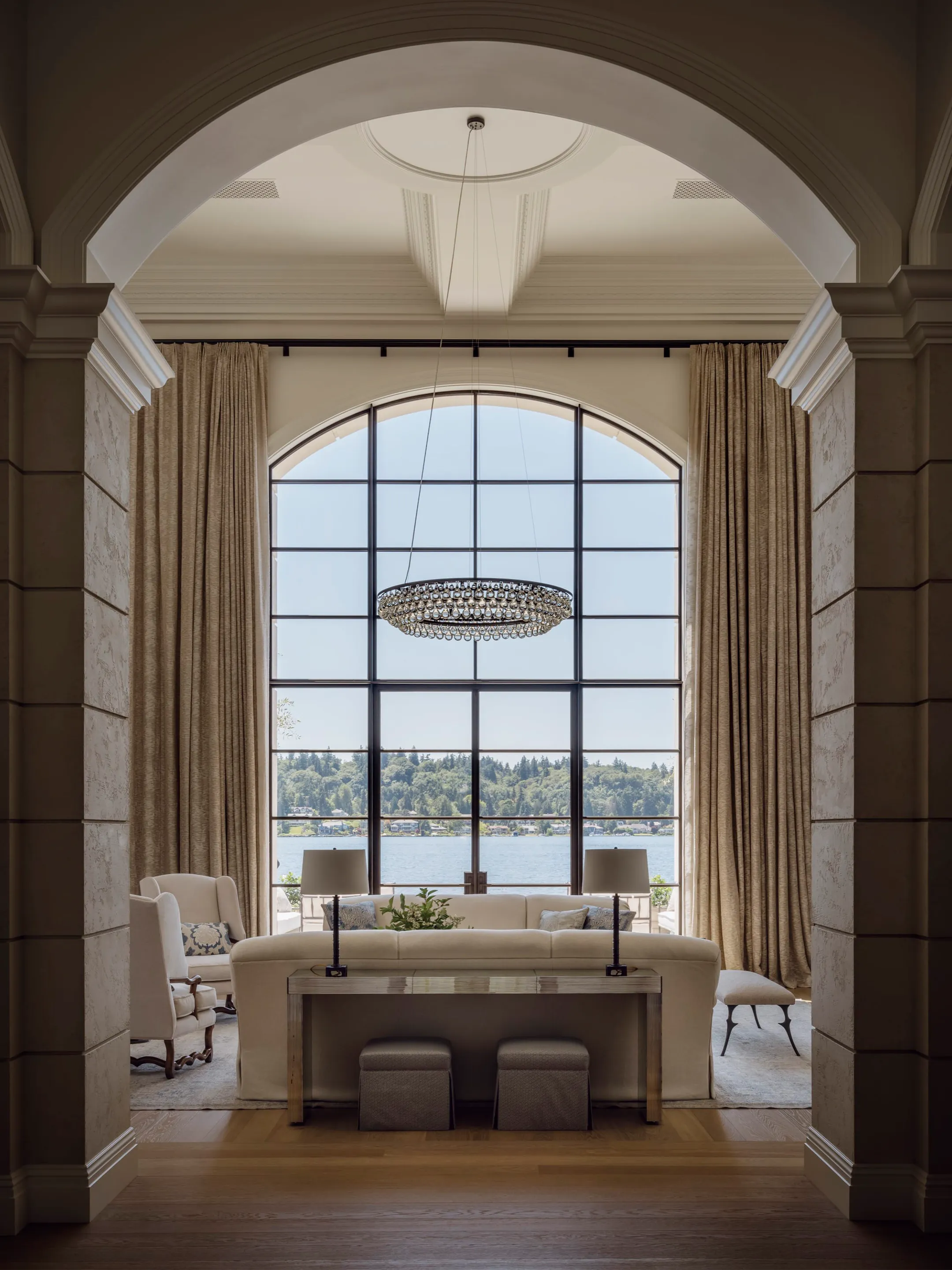 Arched doorway framing a living room with a tall arched window overlooking the water.