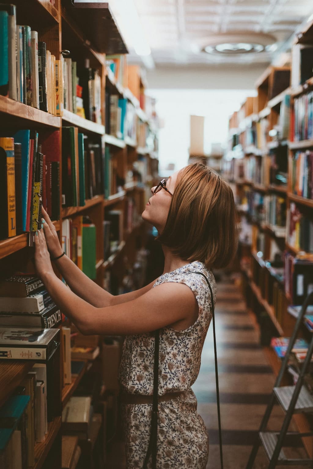 Young woman browsing bookshelves in a library, looking for a book