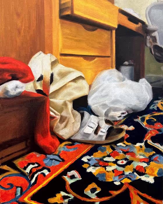 A floor with a bright, patterned carpet, a cardboard box, bags, and shoes.