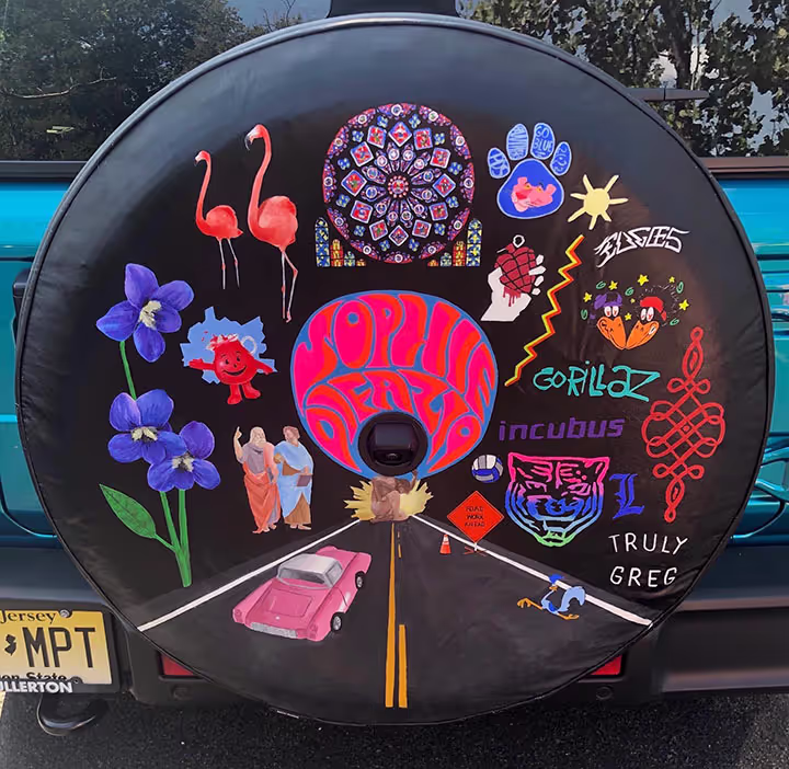 Tire cover painted with a road leading into the center and various things that 17 year old Sophie Difazio was a fan of.