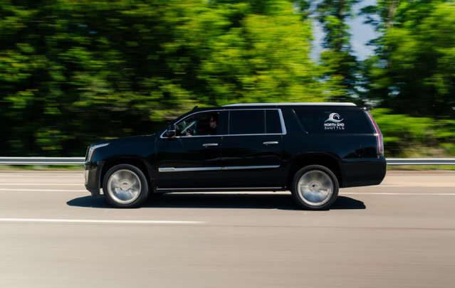 North End Shuttle’s luxury black Cadillac Escalade SUV driving on a highway, offering premium transportation services in Virginia Beach and Hampton Roads.