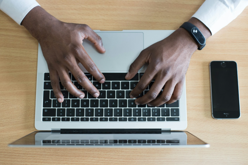 An overhead view of a professional using a laptop and smartphone on a wooden desk to manage a smart inbox through AI-powered prioritization and efficiency tools.