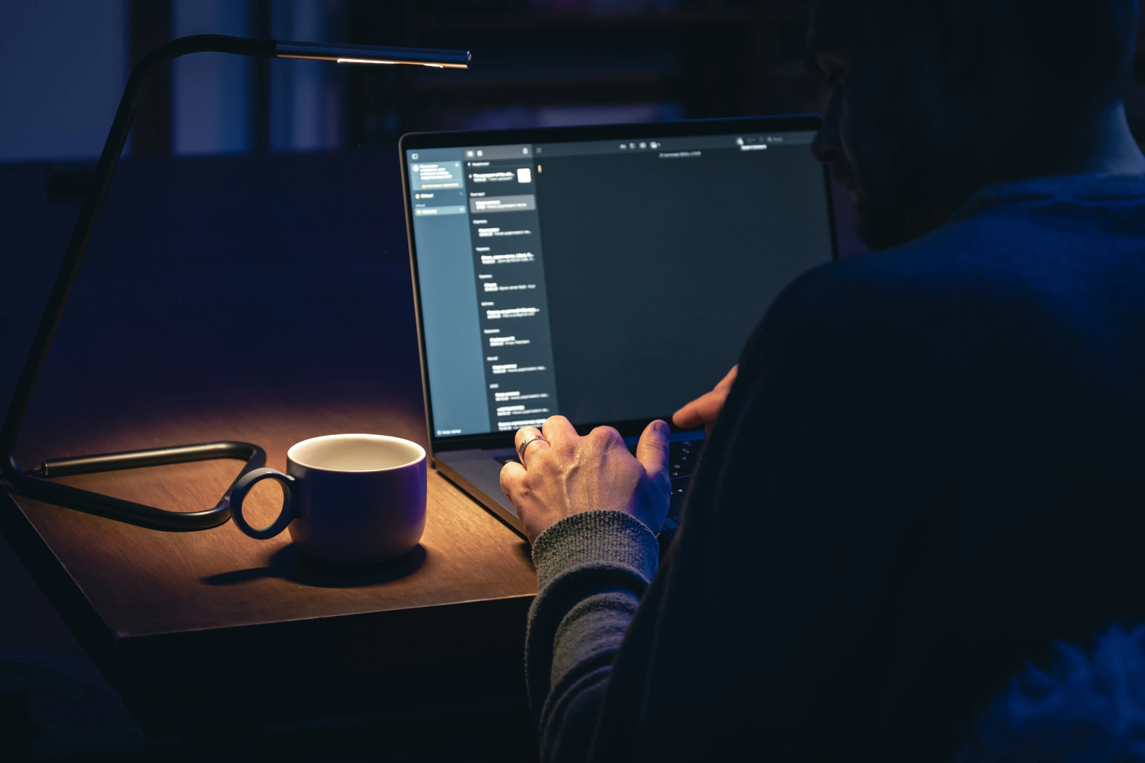 Person working on a MacBook in dark mode, representing Dark Mode on Mac Mail for eye-friendly email management