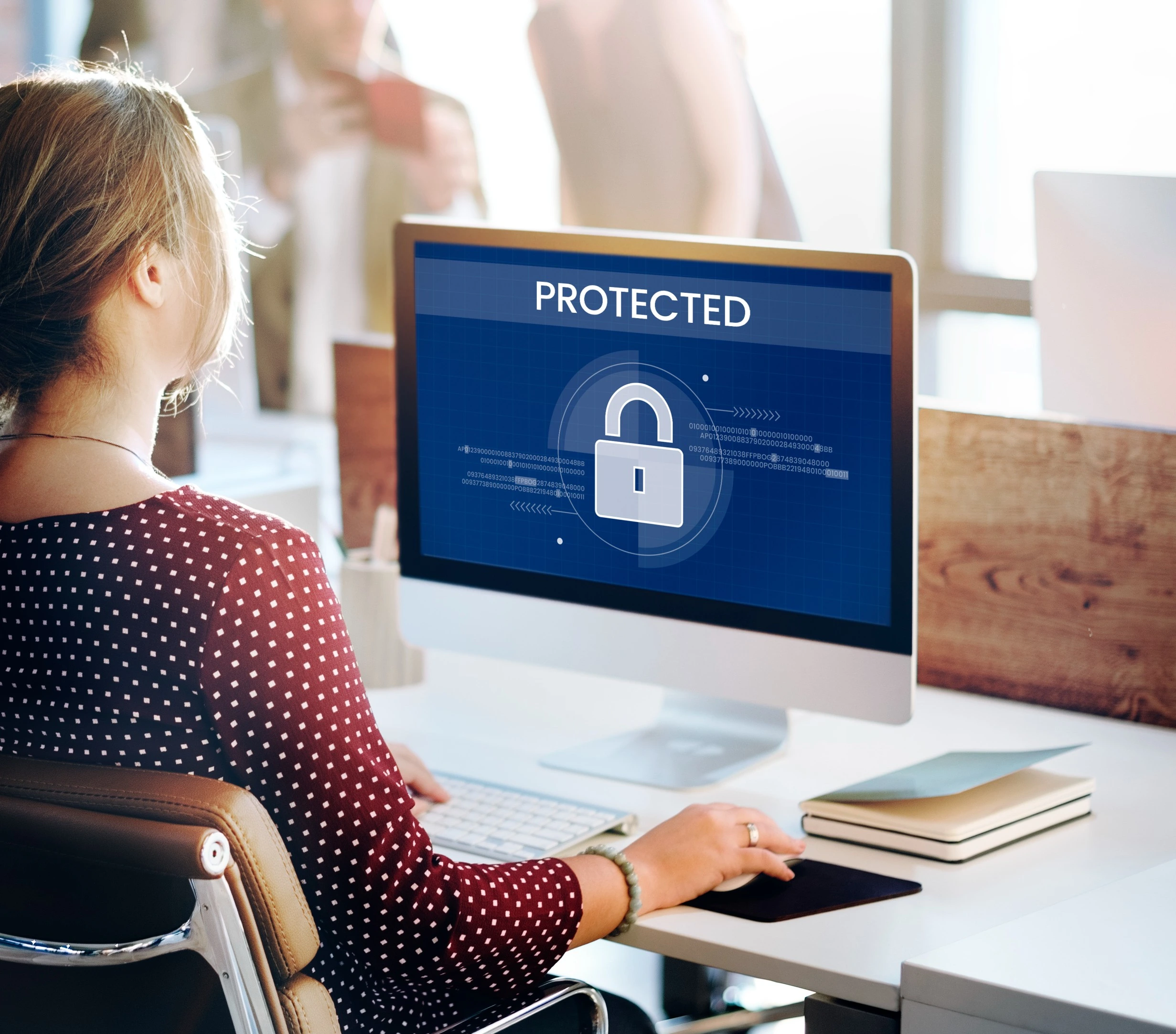A person working at a computer displaying a protected email security screen with a padlock icon