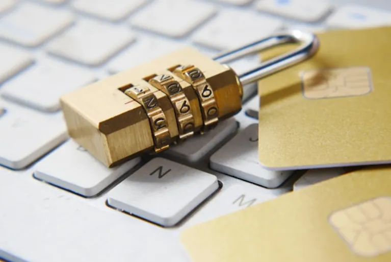 A close-up of a gold combination padlock resting on a white computer keyboard to symbolize the robust protection offered by a secure email client for Mac.