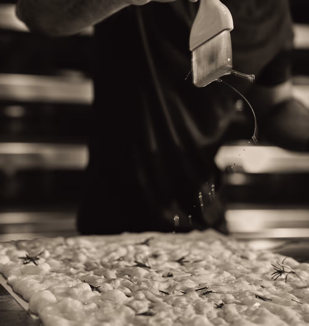 Spreading olive oil over focaccia