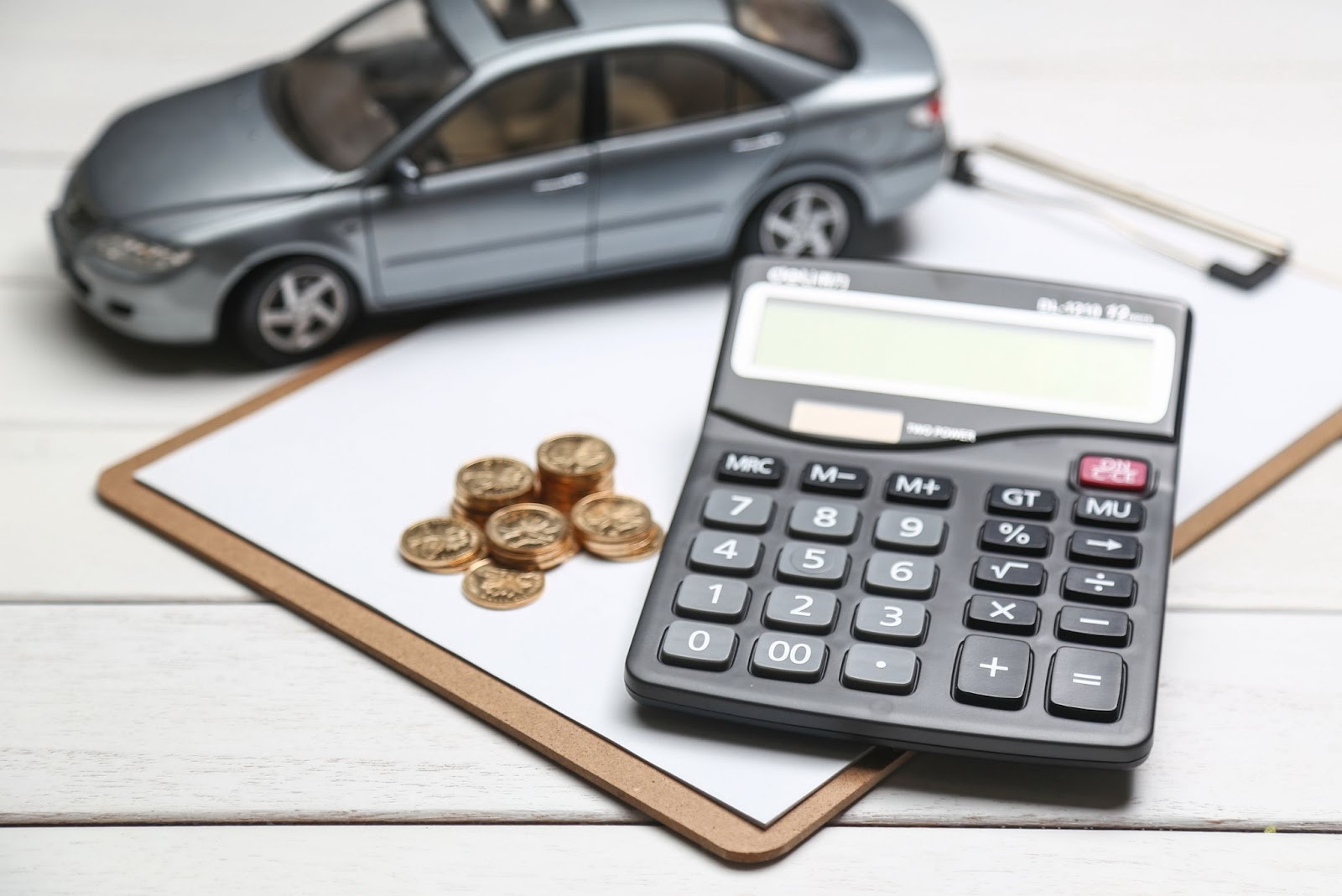 calculadora digital con auto miniatura y monedas