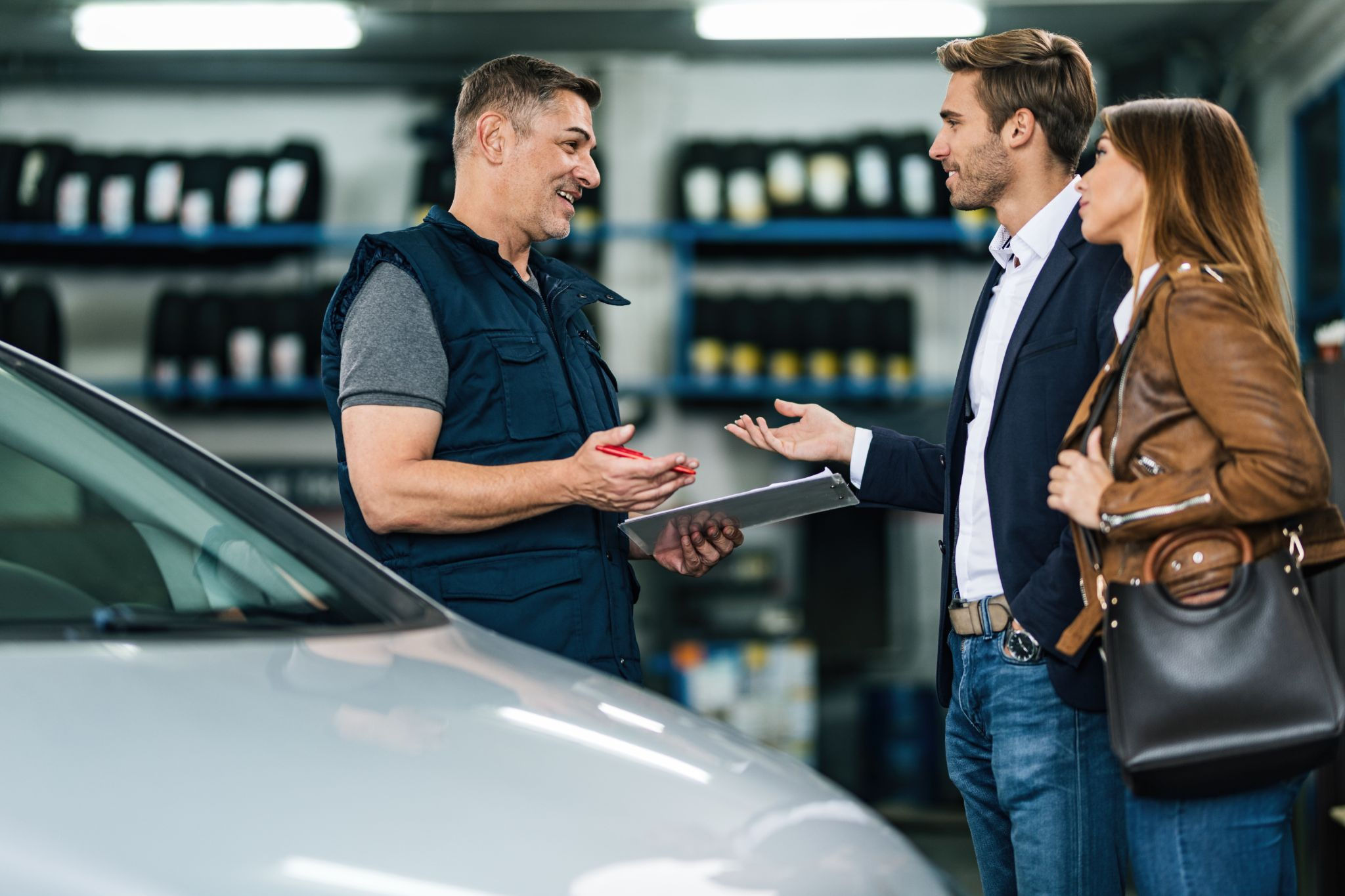 Auto service advisor explaining lease vs buy options to couple at dealership