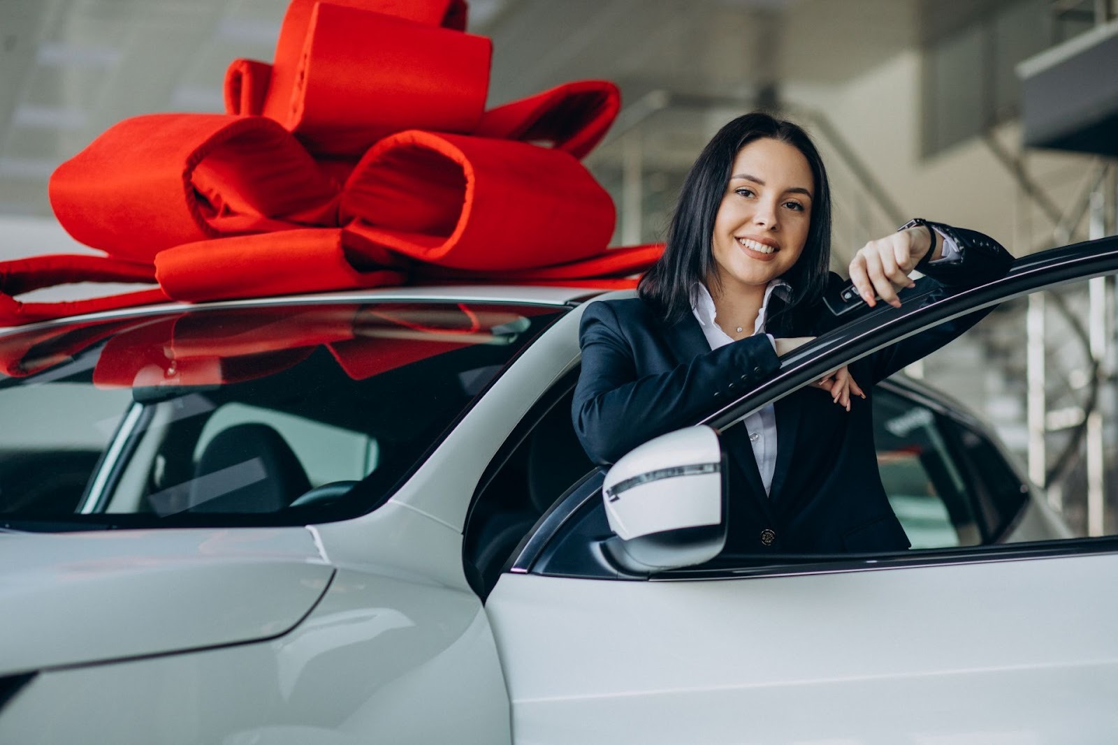 Woman with new car purchase featuring red bow showing lower maintenance cost benefits