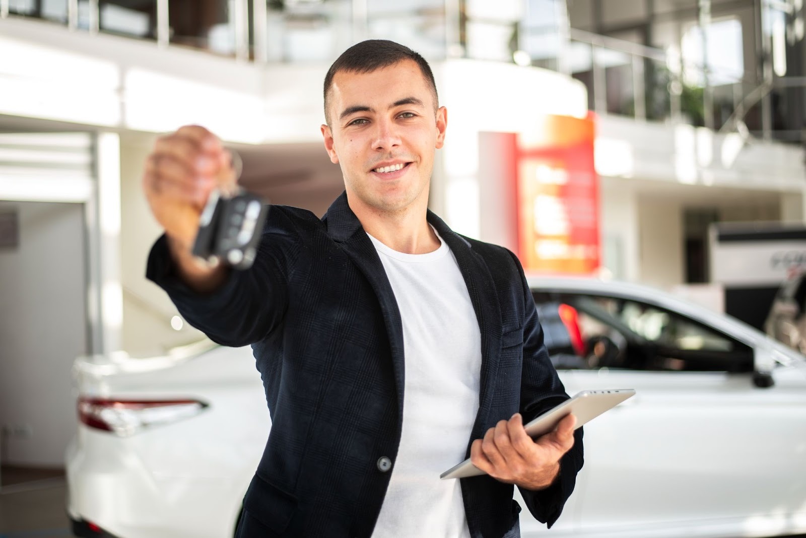 What is the body style of a car: salesman holding keys at automotive dealership showroom