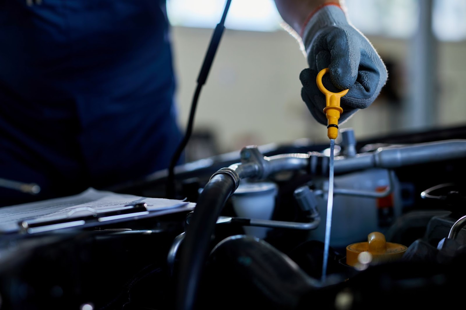 Technician checking synthetic blend engine oil level during car service