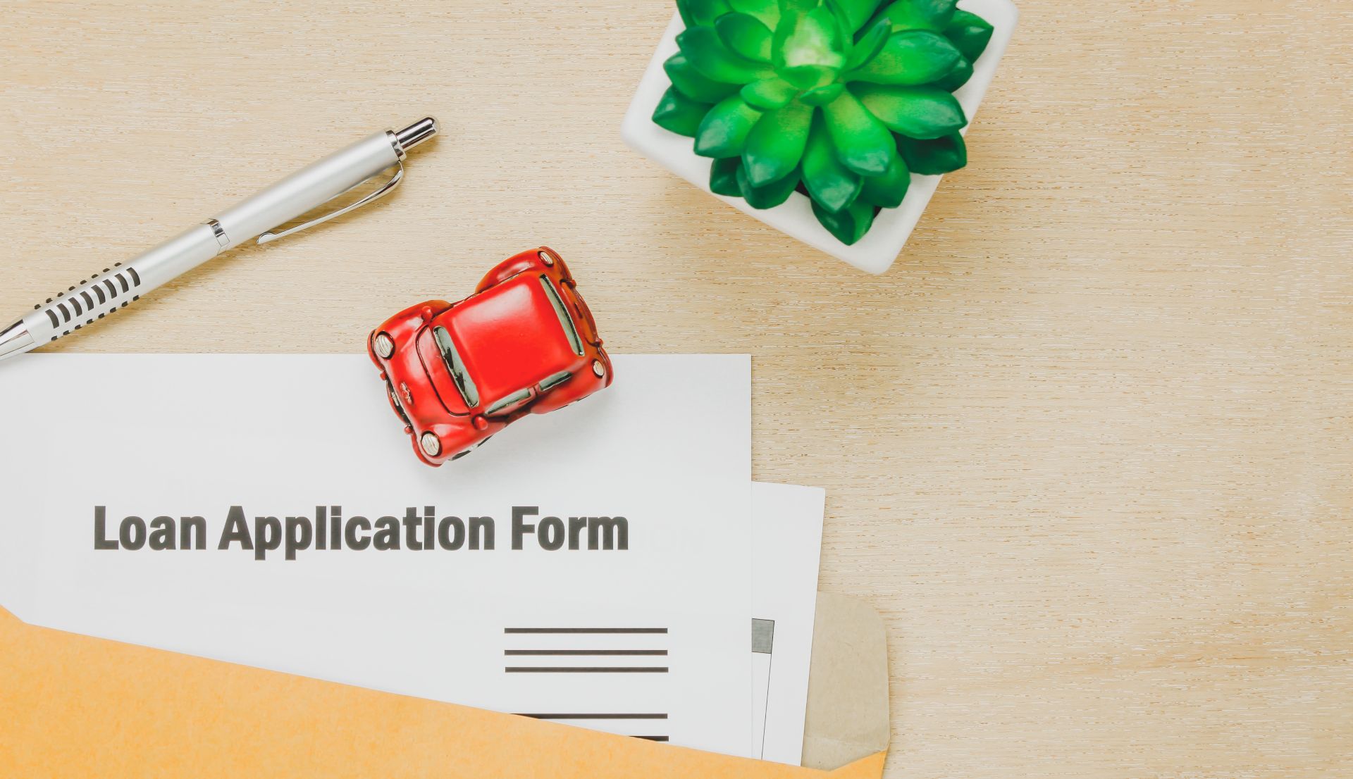 Car loan application form with red toy car and credit score shopping tips