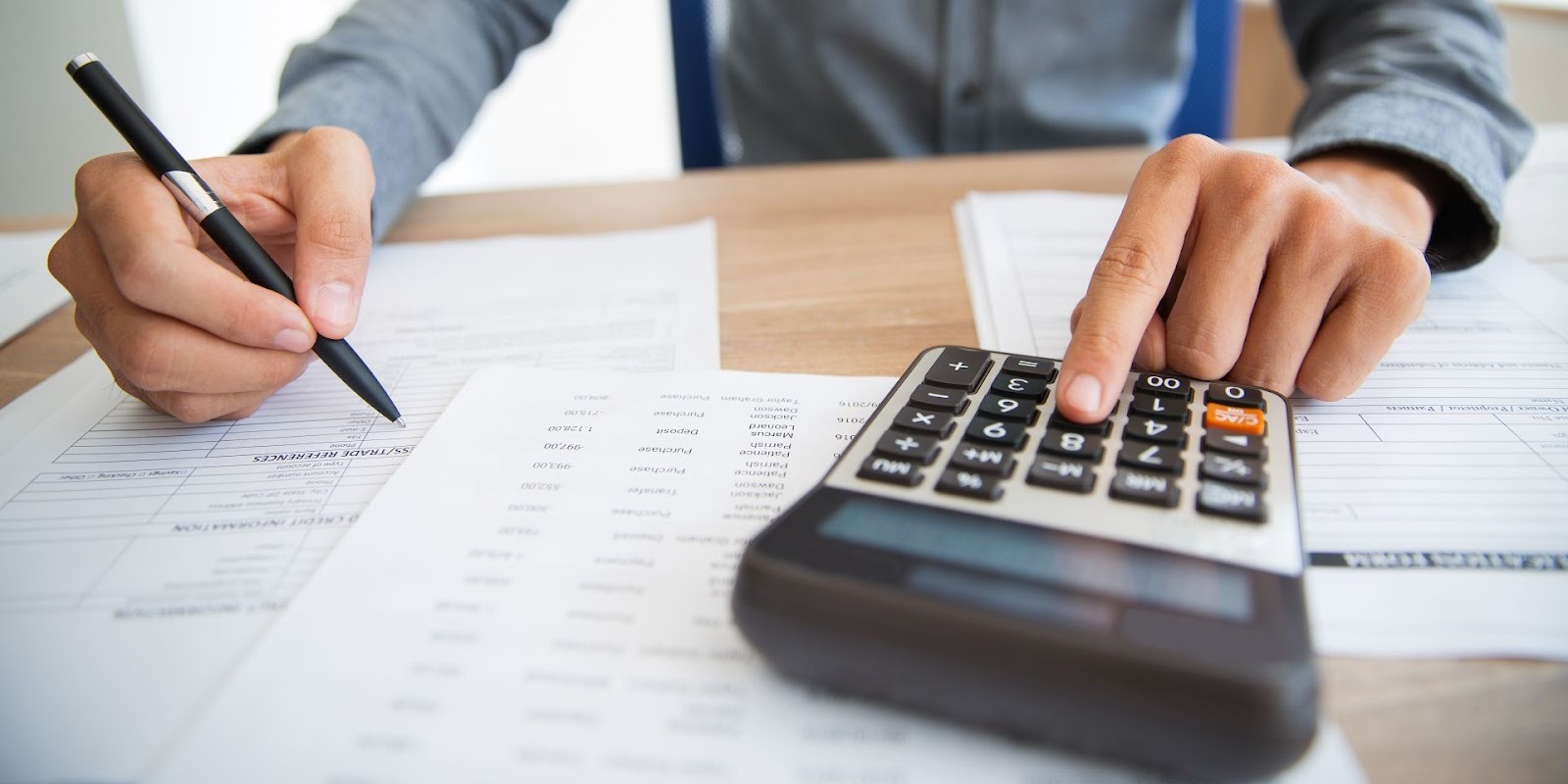 Persona calculando pagos mensuales de préstamo automotriz con documentos y calculadora