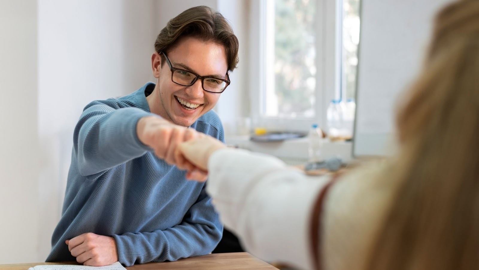 Customer and car sales representative celebrate closing a deal with a friendly fist bump