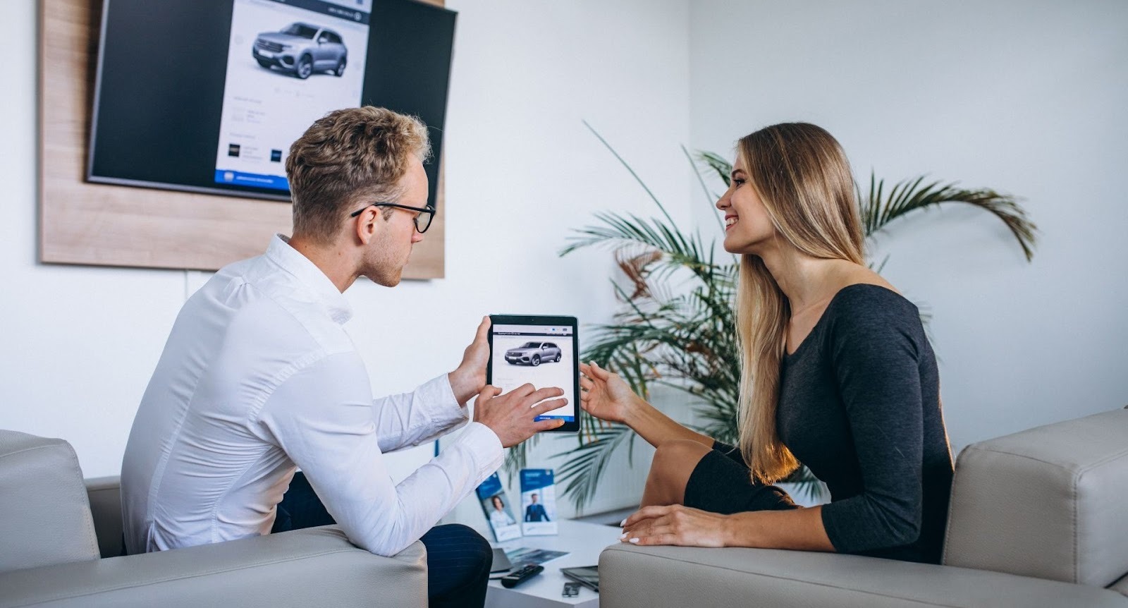 Car concierge presents SUV options on tablet to client at private consultation office