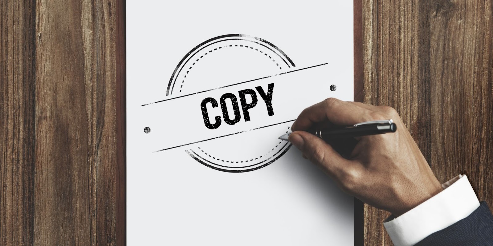 Mano profesional con bolígrafo estampando sello oficial de copia en documento sobre superficie de madera