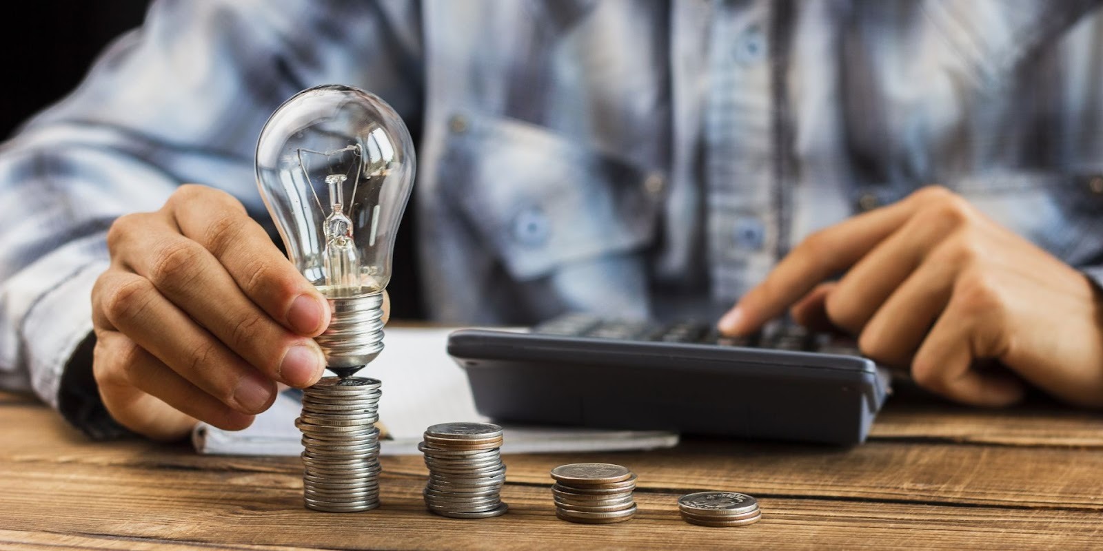 Persona calculando ahorro para enganche de auto con monedas apiladas y calculadora