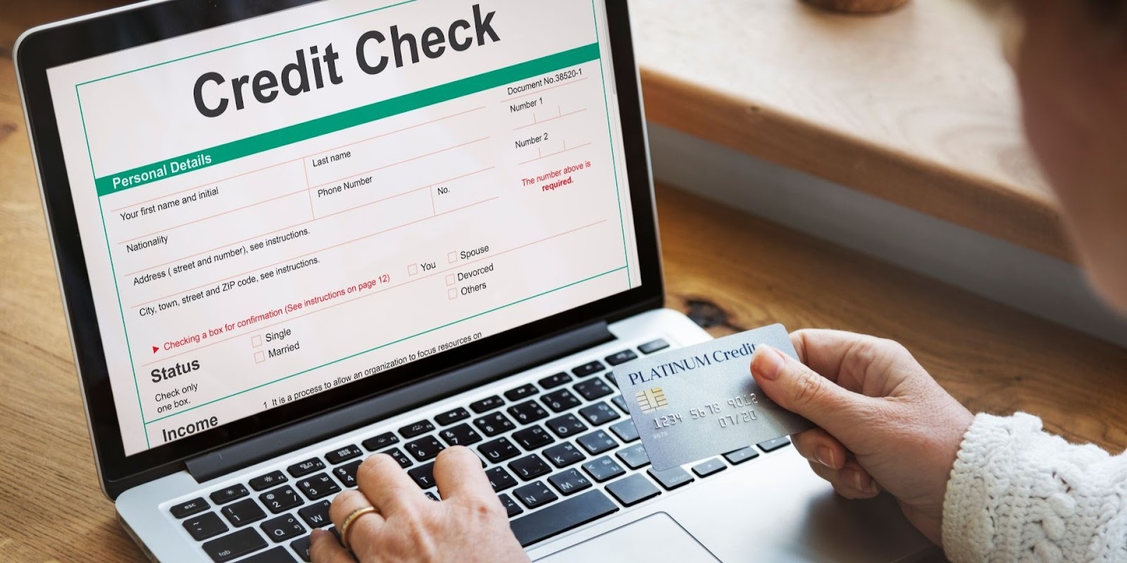 Person completing online credit check application while holding platinum credit card for auto financing