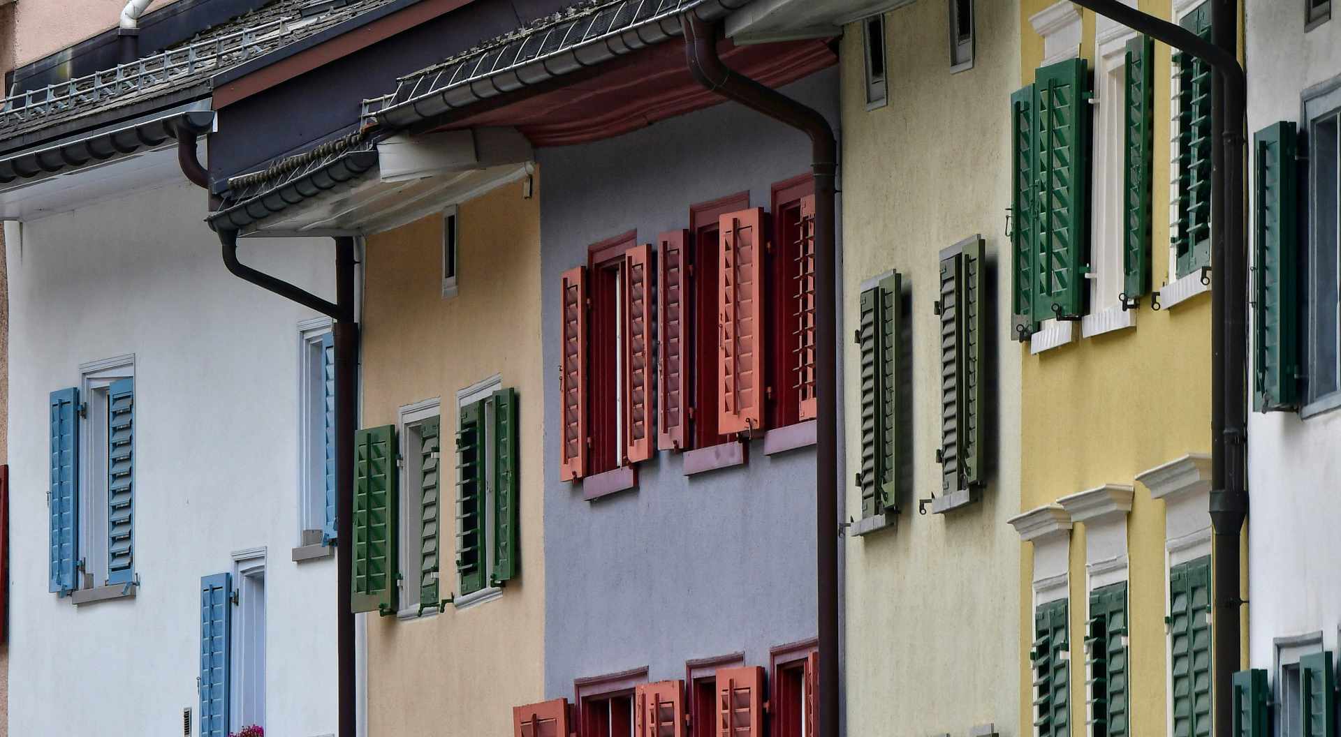 Reihenhäuser mit bunten Fensterläden in Blau, Grün, Rot und Gelb an den Wänden.