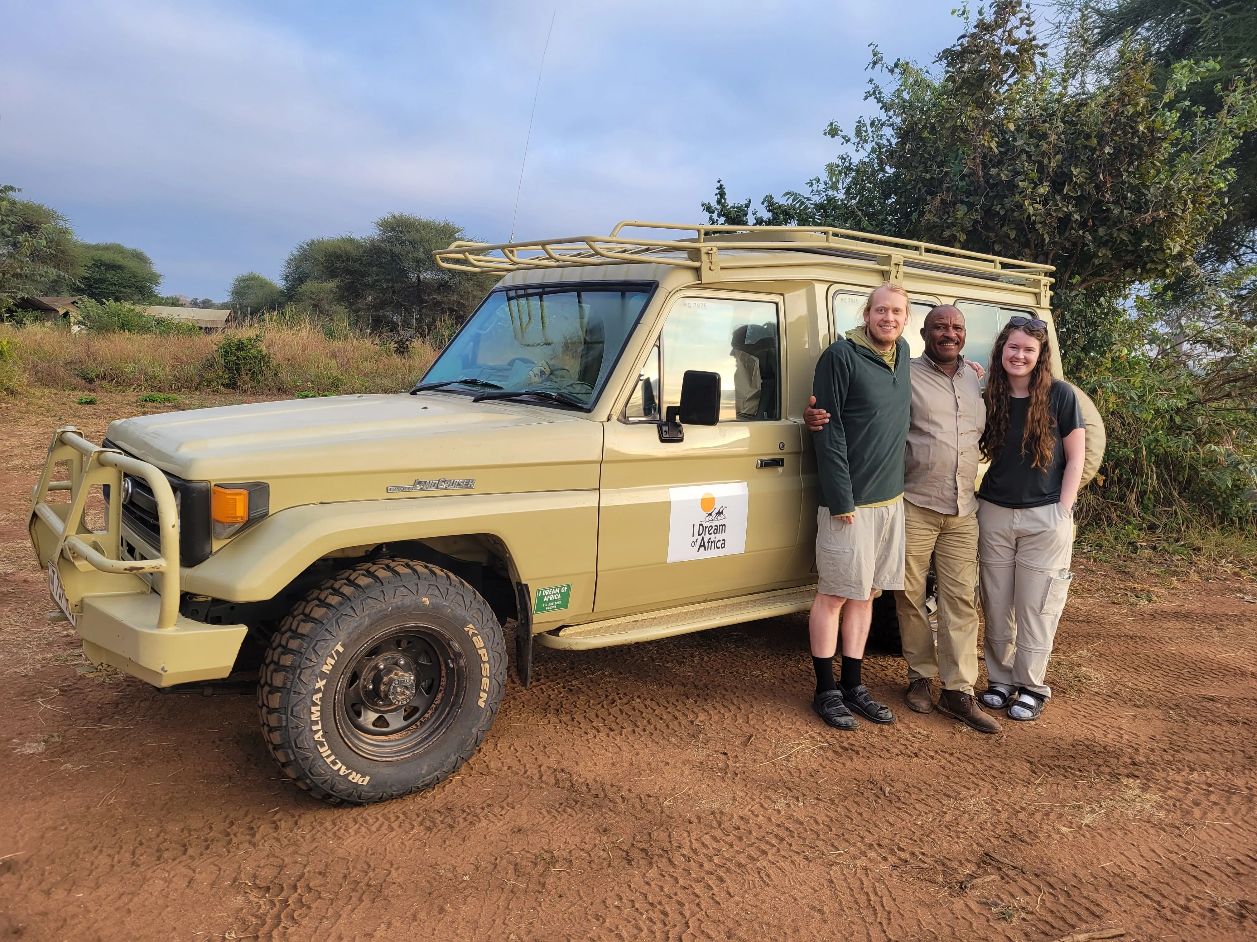 Christopher poses with 2 clients in front of I Dream of Africa safari vehicle in 2024