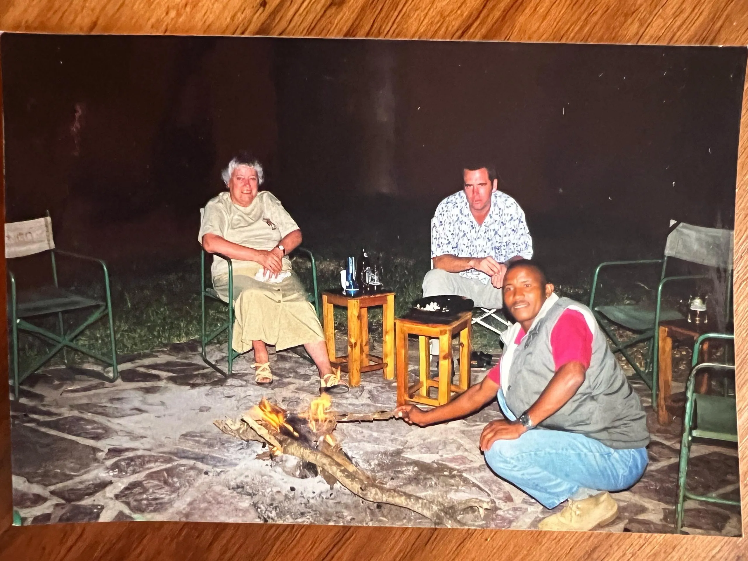 Christopher and 2 clients sit around the fire on safari in 2003