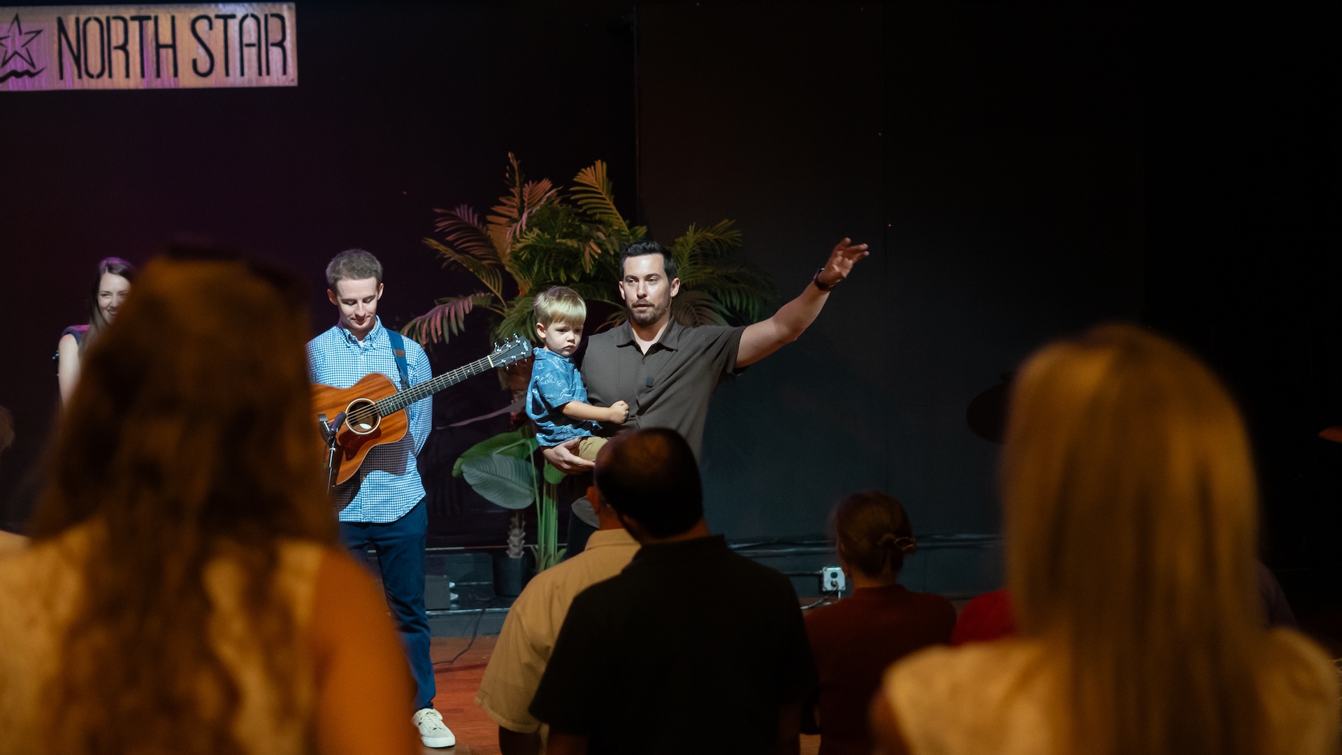 A photo of Rob Russell holding his son and speaking to the church on launch Sunday for Restoration Community Church in Mandeville, LA