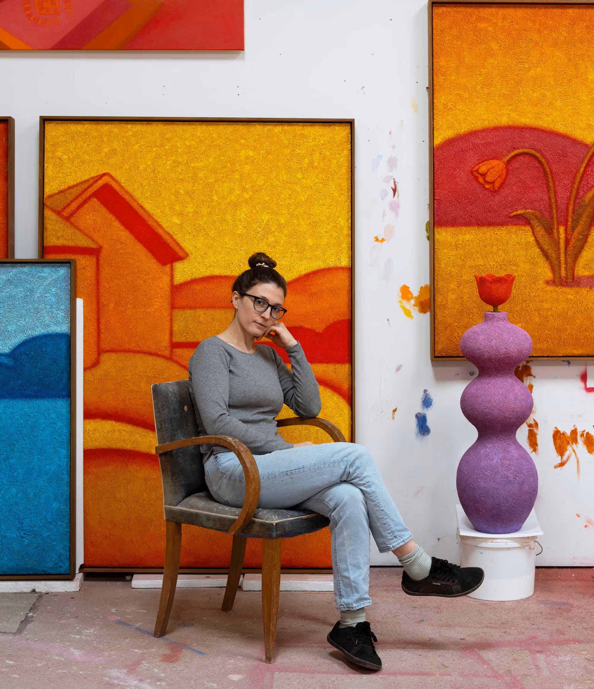 Camilla Maria Dahl with glasses sitting pensively on a wooden chair presenting her show at Opa Projects art gallery in Miami