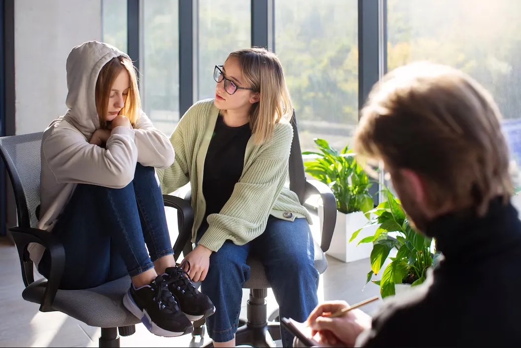 College student talking with a counselor in an office, receiving emotional support.
