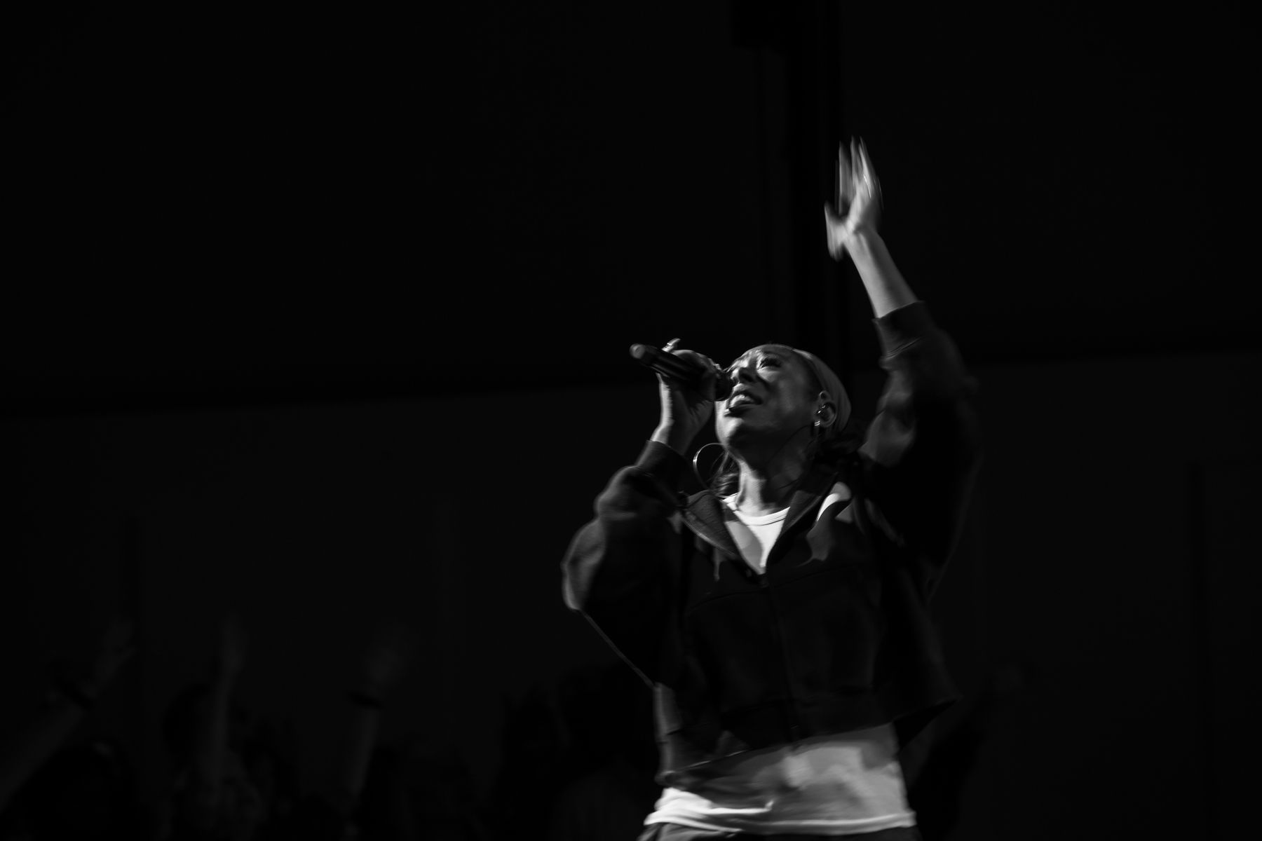 A worship leader singing with one hand raised